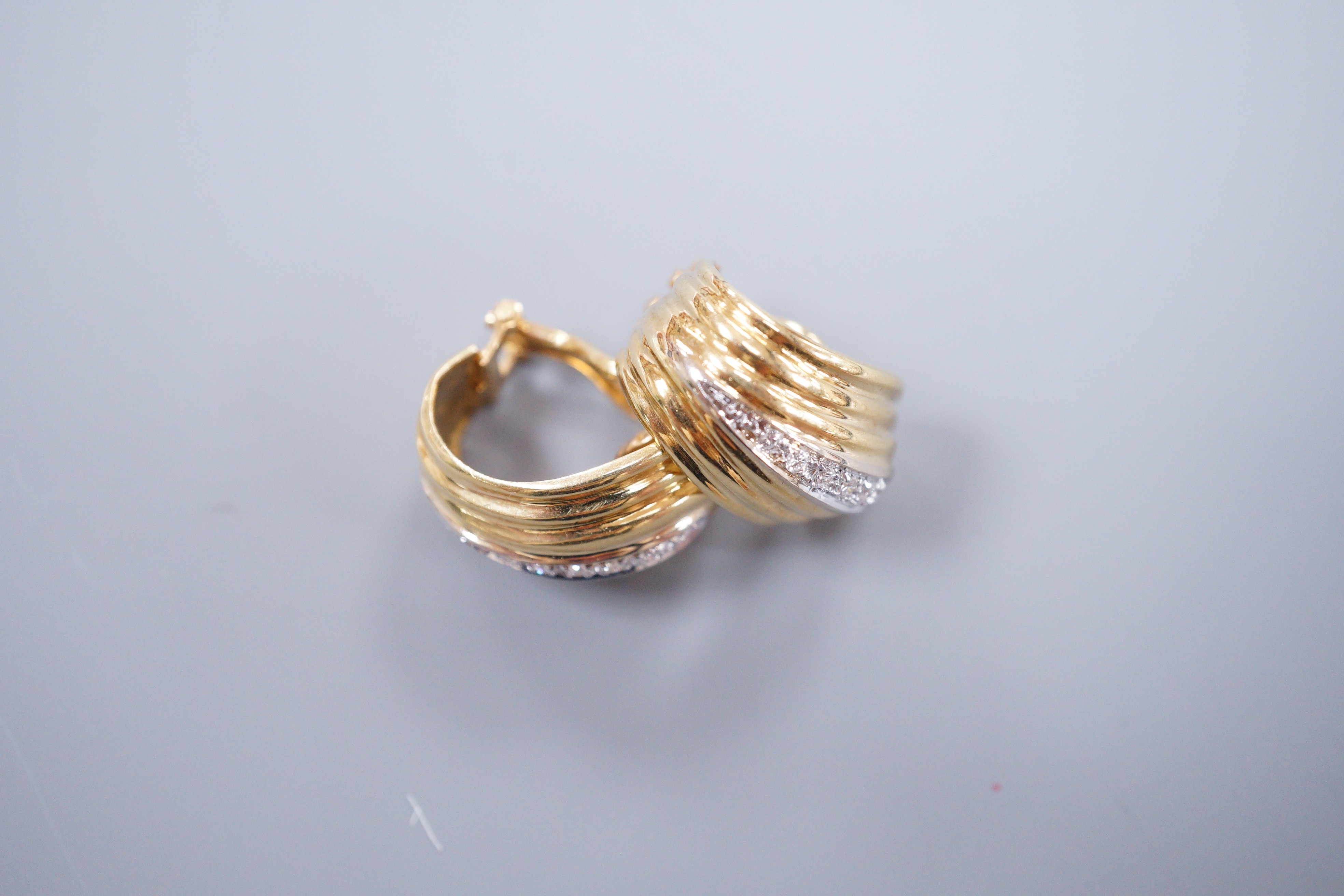 A pair of 18k yellow metal and diamond chip scroll shaped ear-clips, 2cm, gross 13 grams